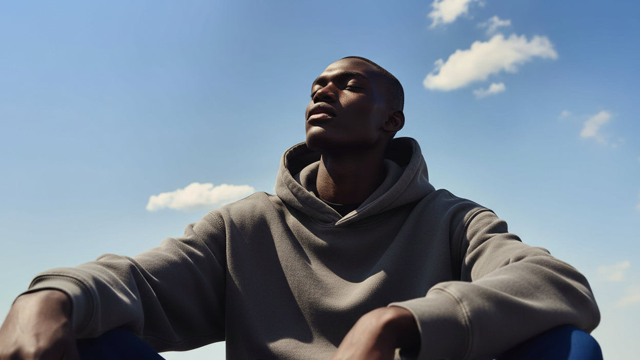 Man in black t-shirt against a blue sky with clouds
